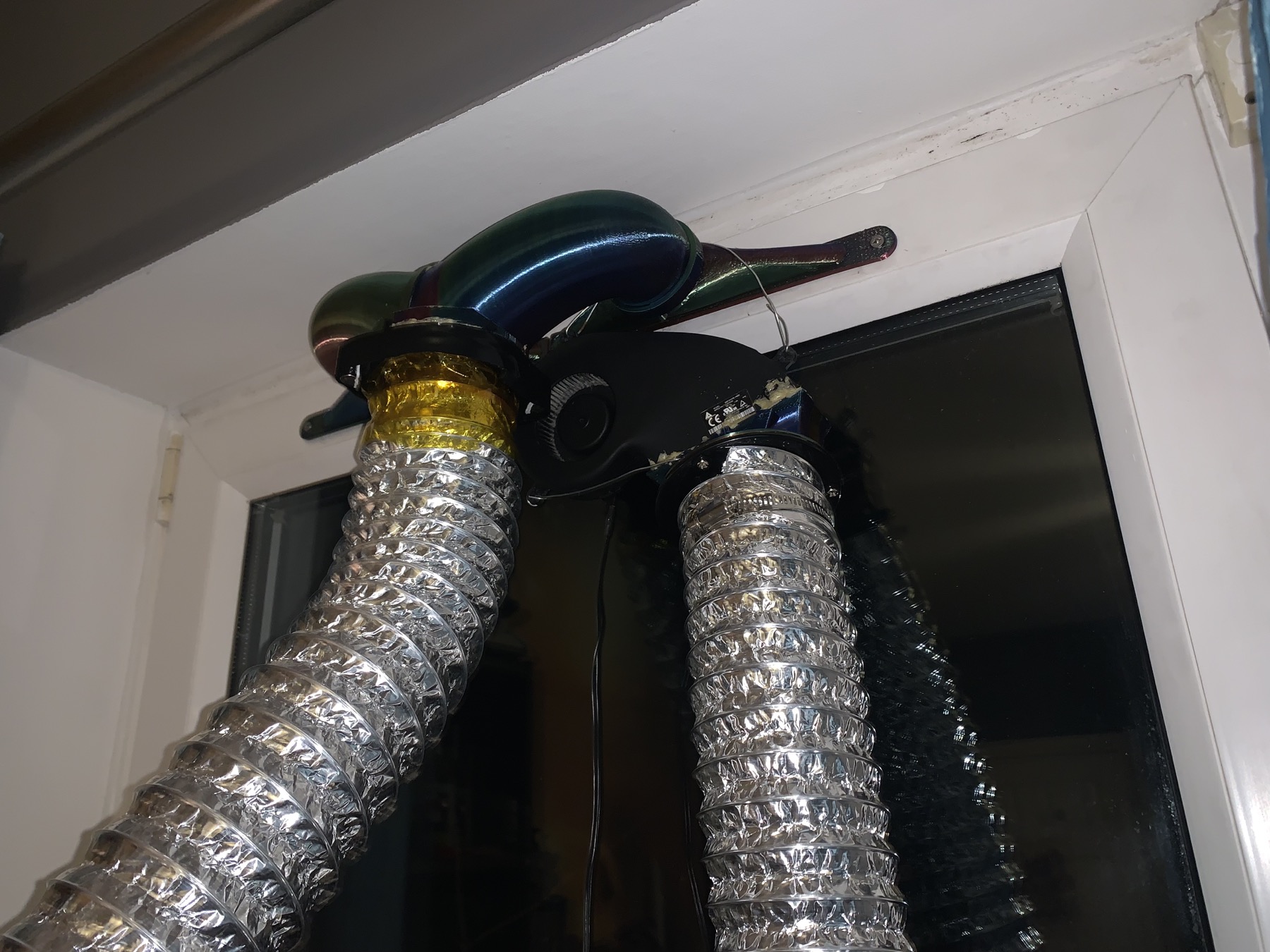 Two extraction fans slung beside the twin duct outlets at the window