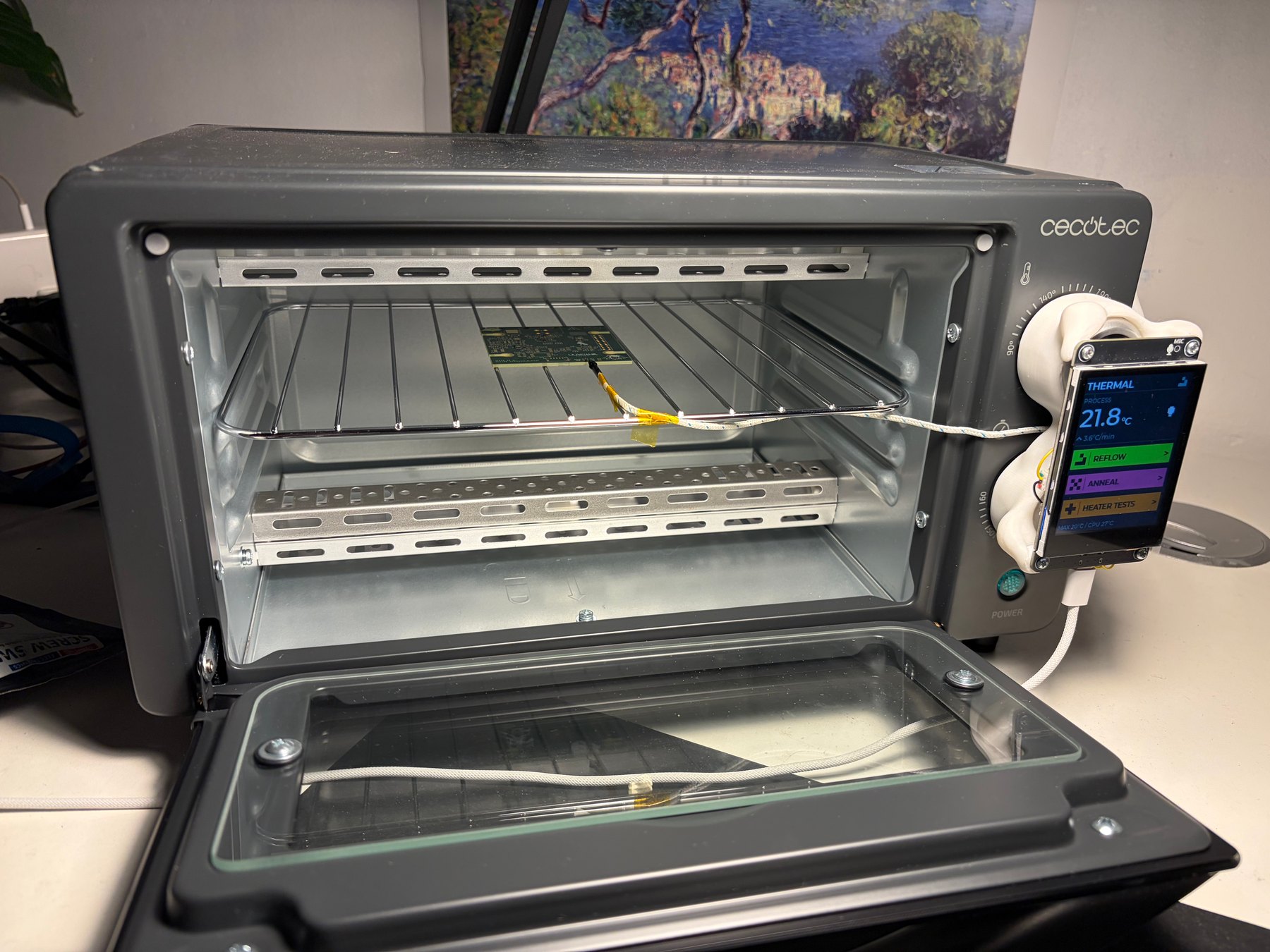 Open oven with a Mu PCB on the rack and the thermocouple sleeve taped with Kapton and bent down onto the board