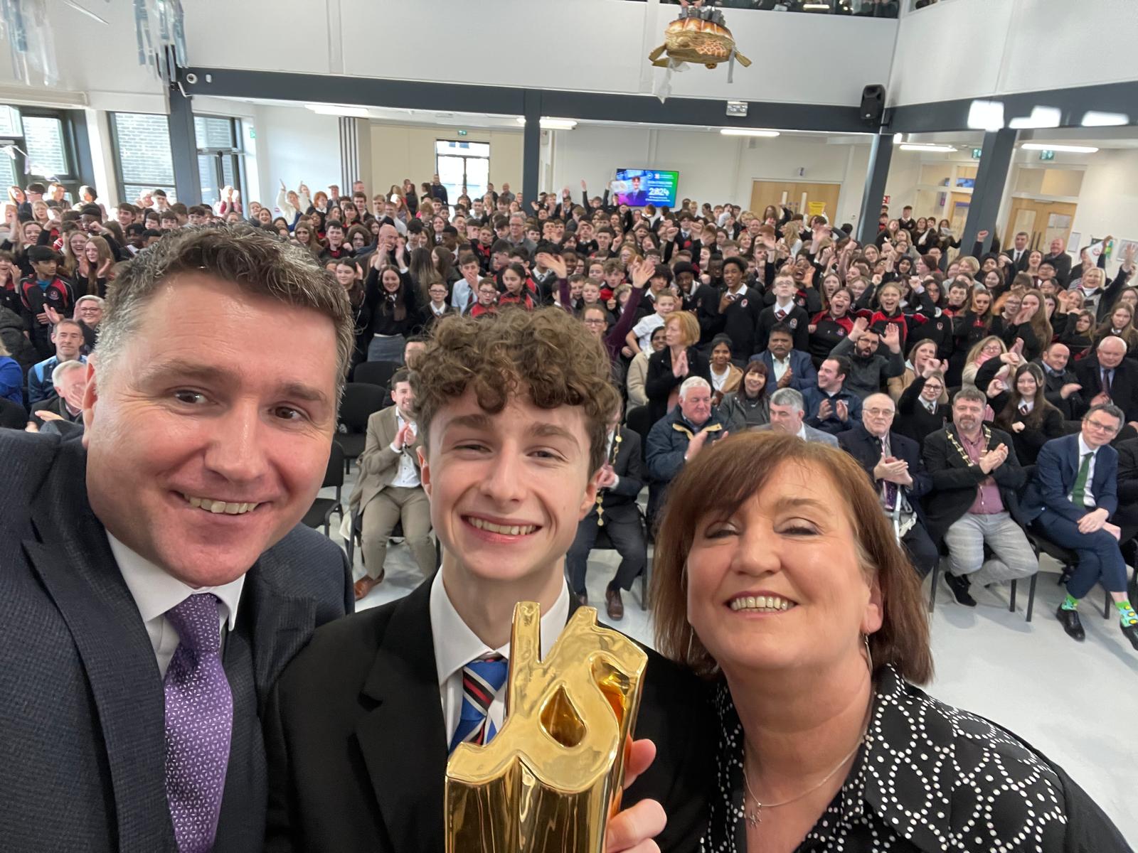 Seán holding the BTYSTE trophy during a welcome-back event at Coláiste Chiaráin