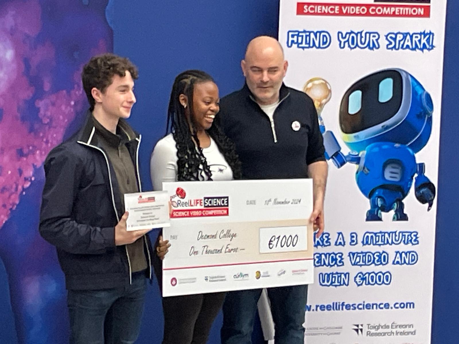 Seán on stage with a ReelLIFE SCIENCE award recipient in November 2024